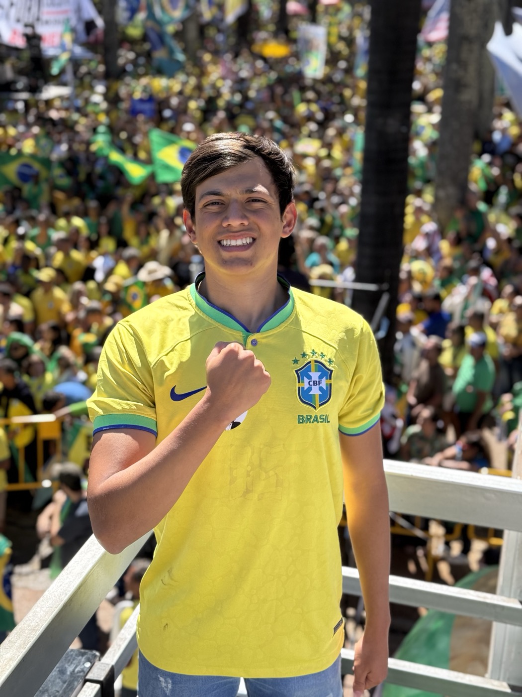 Rafael Lima de camisa da seleção brasileira, sorrindo, com grande multidão verde e amarela ao fundo
